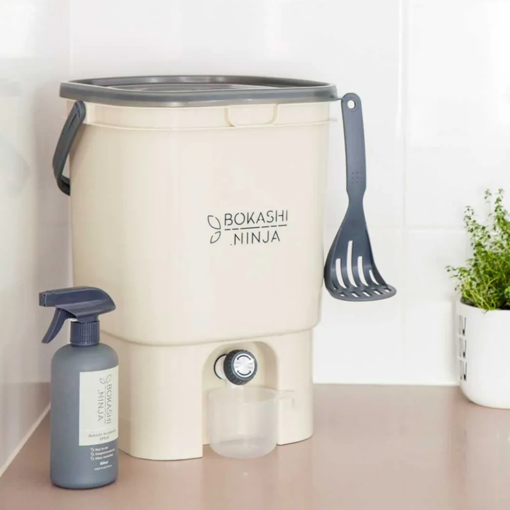A white and grey Bokashi Ninja Compost Bin sitting on a kitchen bench