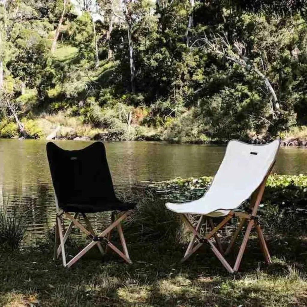 two black and while folding garden chairs positioned by a lake.